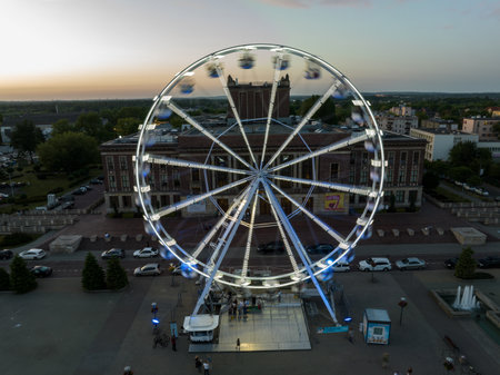 Colorful Ferris wheel From a bird's eye view drone at night. Large colorful Ferris wheel in city center. Aerial drone view on Colorful Ferris wheel spinning in the city center Dabrowa Gornicza Poland.の写真素材