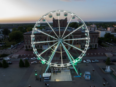 Colorful Ferris wheel From a bird's eye view drone at night. Large colorful Ferris wheel in city center. Aerial drone view on Colorful Ferris wheel spinning in the city center Dabrowa Gornicza Poland.の写真素材