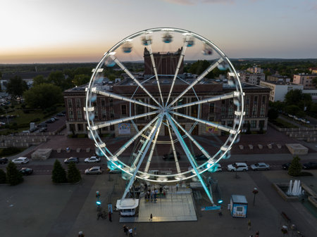 Colorful Ferris wheel From a bird's eye view drone at night. Large colorful Ferris wheel in city center. Aerial drone view on Colorful Ferris wheel spinning in the city center Dabrowa Gornicza Poland.の写真素材