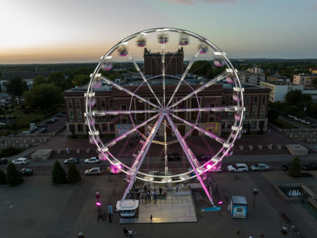 Colorful Ferris wheel From a bird's eye view drone at night. Large colorful Ferris wheel in city center. Aerial drone view on Colorful Ferris wheel spinning in the city center Dabrowa Gornicza Poland.の写真素材