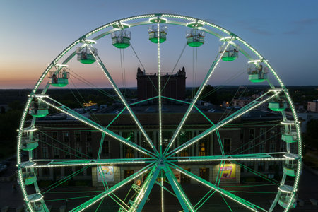 Colorful Ferris wheel From a bird's eye view drone at night. Large colorful Ferris wheel in city center. Aerial drone view on Colorful Ferris wheel spinning in the city center Dabrowa Gornicza Poland.の写真素材