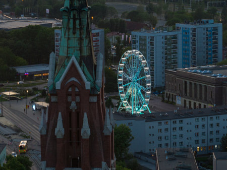 Colorful Ferris wheel From a bird's eye view drone at night. Large colorful Ferris wheel in city center. Aerial drone view on Colorful Ferris wheel spinning in the city center Dabrowa Gornicza Poland.の写真素材