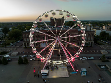 Colorful Ferris wheel From a bird's eye view drone at night. Large colorful Ferris wheel in city center. Aerial drone view on Colorful Ferris wheel spinning in the city center Dabrowa Gornicza Poland.の写真素材