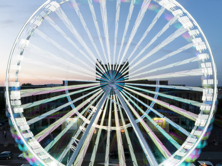 Colorful Ferris wheel From a bird's eye view drone at night. Large colorful Ferris wheel in city center. Aerial drone view on Colorful Ferris wheel spinning in the city center Dabrowa Gornicza Poland.の写真素材
