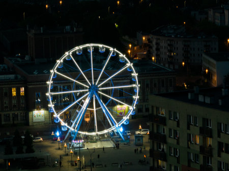 Colorful Ferris wheel From a bird's eye view drone at night. Large colorful Ferris wheel in city center. Aerial drone view on Colorful Ferris wheel spinning in the city center Dabrowa Gornicza Poland.の写真素材