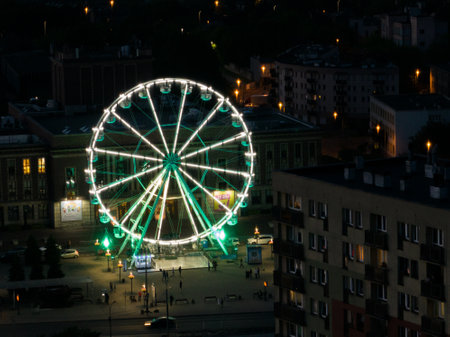 Colorful Ferris wheel From a bird's eye view drone at night. Large colorful Ferris wheel in city center. Aerial drone view on Colorful Ferris wheel spinning in the city center Dabrowa Gornicza Poland.の写真素材