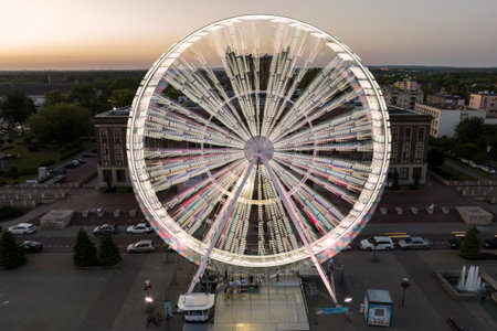 Colorful Ferris wheel From a bird's eye view drone at night. Large colorful Ferris wheel in city center. Aerial drone view on Colorful Ferris wheel spinning in the city center Dabrowa Gornicza Poland.の写真素材