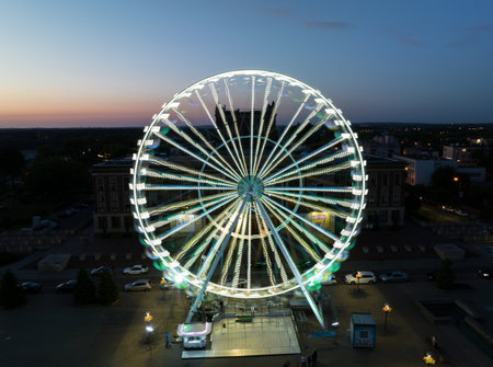Colorful Ferris wheel From a bird's eye view drone at night. Large colorful Ferris wheel in city center. Aerial drone view on Colorful Ferris wheel spinning in the city center Dabrowa Gornicza Poland.の写真素材