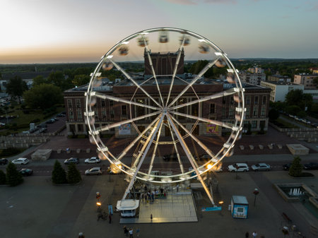 Colorful Ferris wheel From a bird's eye view drone at night. Large colorful Ferris wheel in city center. Aerial drone view on Colorful Ferris wheel spinning in the city center Dabrowa Gornicza Poland.の写真素材