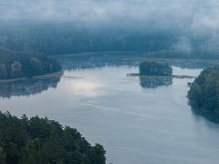Aerial drone view of a lake surrounded by green forest. Big lake in the fog and clouds. Kulka Reserve, Masuria, Poland. Lake in the Masurian Lake District. Lake Lesk in the Kulka Reserve in Poland.の写真素材