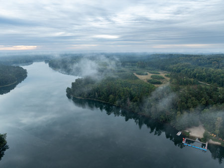 Aerial drone view of a lake surrounded by green forest. Big lake in the fog and clouds. Kulka Reserve, Masuria, Poland. Lake in the Masurian Lake District. Lake Lesk in the Kulka Reserve in Poland.の写真素材