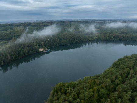 Aerial drone view of a lake surrounded by green forest. Big lake in the fog and clouds. Kulka Reserve, Masuria, Poland. Lake in the Masurian Lake District. Lake Lesk in the Kulka Reserve in Poland.の写真素材