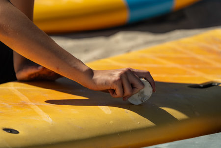 Surfboard wax. Waxing and surfboarding. Hand holds a piece of surf wax and applies it to the surfboard.の写真素材