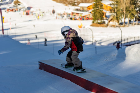 Snow park box tricks. Snowboarder in park on a box. Winter jibbing in snwopark. Snowboard lessons on...
