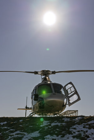Helicopter on a snowy mountain helipad with a picturesque alpine backdrop. Helicopter, sightseeing flights over the Dolomites and Alps. The helicopter is standing on a landing field in the mountains.の写真素材