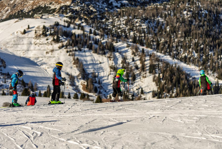 Group of people skiing in the mountains on a sunny winter day. Ski lessons with local instructors. Children learn to ski with an instructor. Children's skiers in the Dolomites Alps.の写真素材