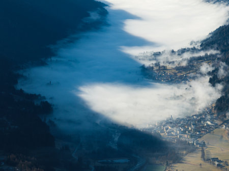 Aerial drone view of sunny winter in dolomites, alps.Pinzolo village and a ski resort in Italy. Dolomites Brenta, town in Dolomites covered in fog, view from a drone.の写真素材
