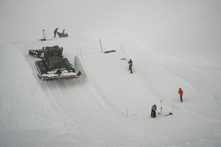 Ski resort snow grooming with cable car and workers preparing a freestyle park. Shapers preparing kicker in snowpark. Madonna di Campiglio ursus snowpark in Val Rendena dolomites trentino Italy.の写真素材