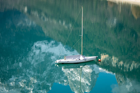 Sailboat on crystal clear lake in the Brenta Dolomites. Aerial drone view of Lake Molveno, beautiful lake in Italy. Lake in dolomites from drone in winter. Lake Molveno in Italy.の写真素材