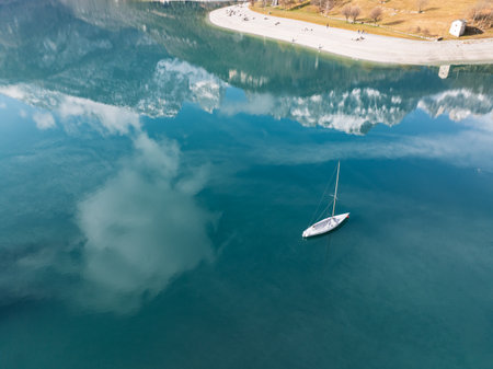 Sailboat, yacht on crystal clear lake in the Brenta Dolomites. Aerial drone view of Lake Molveno, beautiful lake in Italy. Lake in dolomites from drone in winter. Lake Molveno in Italy.の写真素材