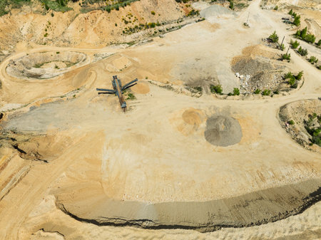 Aerial drone view of sand or gravel quarry surrounded by forest and farmland with distant hills. Drone view shows an inactive or abandoned quarry embedded in a green landscape.の写真素材
