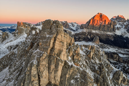 Aerial view of a winter sunrise on Giau Pass in Italian Dolomites.Snow covered mountain road. Majestic alpine peaks and warm morning light. Cinque Torri in the Dolomites. Sunrise in winter dolomites.の写真素材