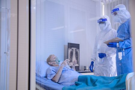 Infected patient on takecare of Doctor and nurse with x-ray Lung in quarantine lying on bed in...