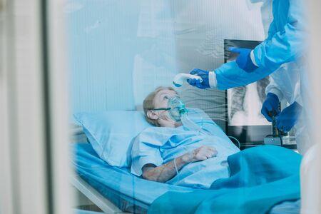 Infected patient lying on bed in hospital under care of Medical team with X-rays Lung in quarantine room from coronavirus covid 19 disease.の写真素材