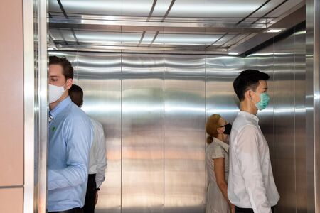 Social Distancing on Elevator with 4 passengers stand in the corner from outbreak of coronavirus...
