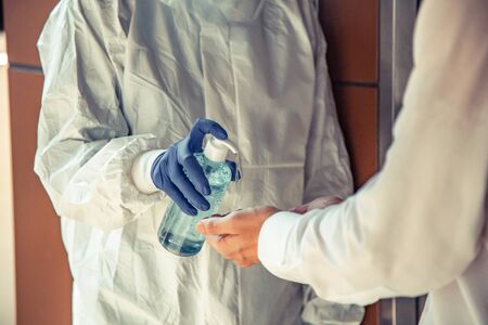 Officer Squeezing gel to people hands for wash hand by sanitizer gel dispenser, against Novel coronavirus or Corona Virus Disease (Covid-19) at front office. Antiseptic, Hygiene and Healthcare conceptの写真素材