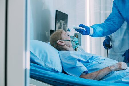 Old woman patient laying on bed with background of the medical team thumbs up after recovered from coronavirus or COVID19. Concept of success discover vaccine and teamwork.の写真素材