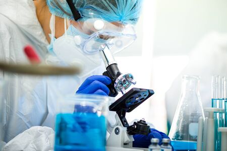 Scientist or researcher hand in blue gloves holding flu, measles, coronavirus, covid-19 vaccine...