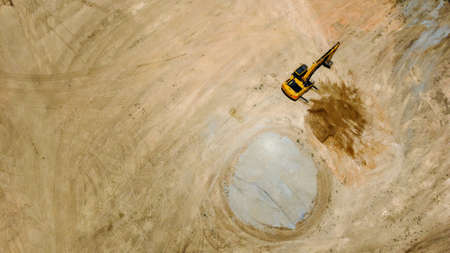 Backhoe or Excavator scraping a layer of soil from bird eye view by drone
