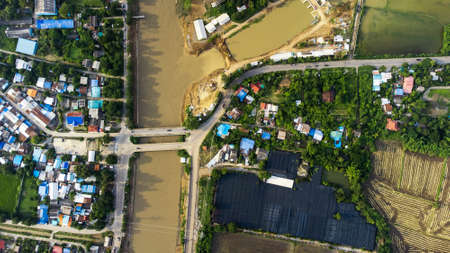 Tha Ruea, Ayutthaya, Thailand - October 2021: Flood waters overtake a house and rice field in area around Rama 6 Dam (Phra Narai Gate). Many buildings are submerged in water. Photo disaster from droneのeditorial素材