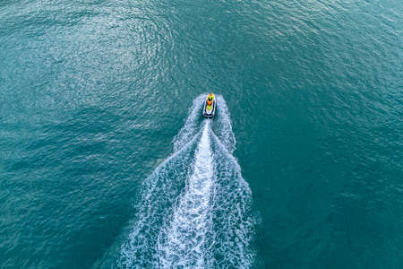 Sichon beach, Thailand - November 2021 : Aerial bird eyes view of Unidentified jet ski inclouding banana boat behide cruising in high speed in turquoise clear water sea.のeditorial素材