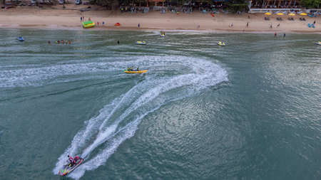 Sichon beach, Thailand - November 2021 : Aerial bird eyes view of Unidentified jet ski inclouding banana boat behide cruising in high speed in turquoise clear water sea.のeditorial素材
