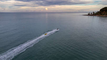 Sichon beach, Thailand - November 2021 : Aerial bird eyes view of Unidentified jet ski inclouding banana boat behide cruising in high speed in turquoise clear water sea.のeditorial素材