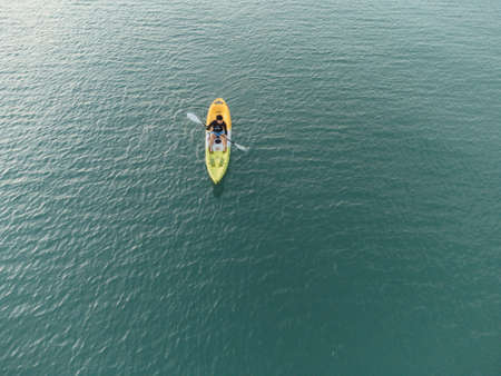 Gulf of Thailand - Ocotber 2021 : Unidentified man on sea Kayaker Aerial View. Caucasian Sportsman in the Yellow and Blue Kayak Paddling on the Scenic sea Along the Shore.のeditorial素材