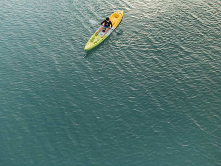 Gulf of Thailand - Ocotber 2021 : Unidentified man on sea Kayaker Aerial View. Caucasian Sportsman in the Yellow and Blue Kayak Paddling on the Scenic sea Along the Shore.のeditorial素材