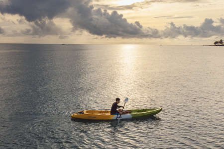 Gulf of Thailand - Ocotber 2021 : Unidentified man on sea Kayaker Aerial View. Caucasian Sportsman in the Yellow and Blue Kayak Paddling on the Scenic sea Along the Shore.のeditorial素材