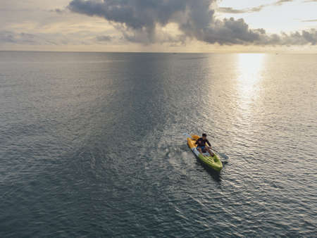 Gulf of Thailand - Ocotber 2021 : Unidentified man on sea Kayaker Aerial View. Caucasian Sportsman in the Yellow and Blue Kayak Paddling on the Scenic sea Along the Shore.のeditorial素材
