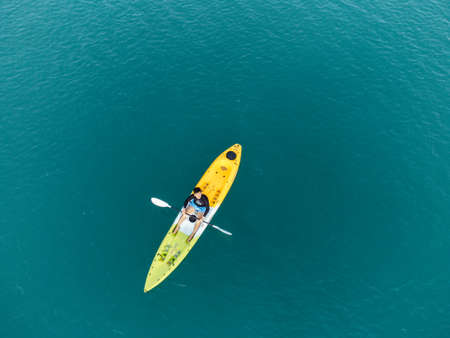 Gulf of Thailand - Ocotber 2021 : Unidentified man on sea Kayaker Aerial View. Caucasian Sportsman in the Yellow and Blue Kayak Paddling on the Scenic sea Along the Shore.のeditorial素材