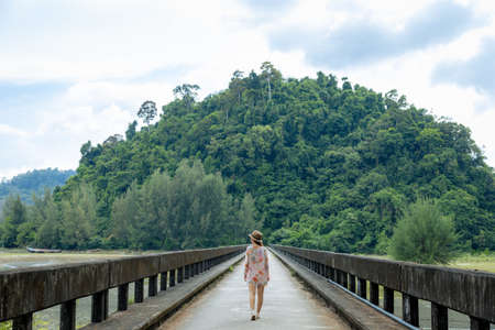 Young woman with hat across bridge over a mountain river in the forest at Laem Son National Park, Ranong, Thailand.の写真素材