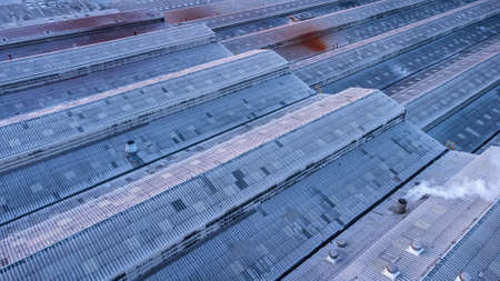Roofs of Factory buildings in heavy industrial with white smoke against blue sky during sunset. Aerial photo view by drone from top of plant.の写真素材