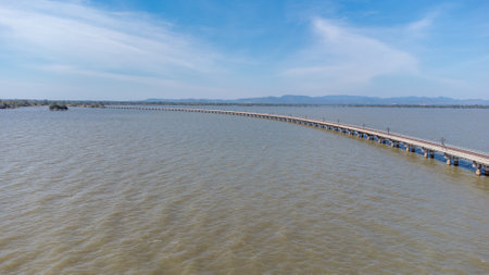 Aerial view of an amazing travel train parked on a floating railway bridge over the water of the lake in Pa Sak Jolasid dam with blue sky at Lopburi, Thailand.の写真素材