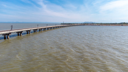 Aerial view of an amazing travel train parked on a floating railway bridge over the water of the lake in Pa Sak Jolasid dam with blue sky at Lopburi, Thailand.の写真素材