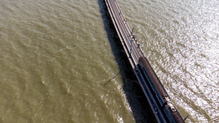 Aerial view of an amazing travel train parked on a floating railway bridge over the water of the lake in Pa Sak Jolasid dam with blue sky at Lopburi, Thailand.の写真素材