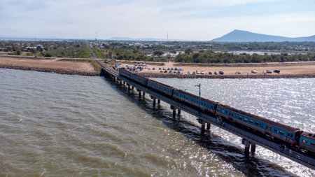 Aerial view of an amazing travel train parked on a floating railway bridge over the water of the lake in Pa Sak Jolasid dam with blue sky at Lopburi, Thailand.の写真素材