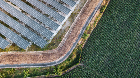 Fly over Solar cells farm beside nature green farm around large industrial factory area. Solar farms are generating renewable energy for the industry.の写真素材