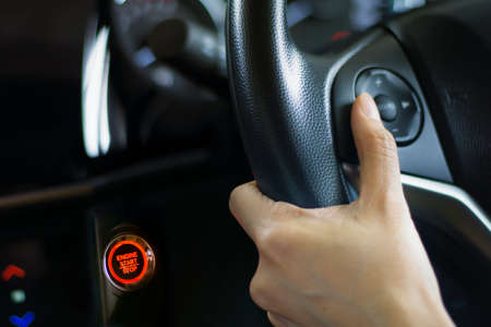 Woman pressing control button on the car steering wheel